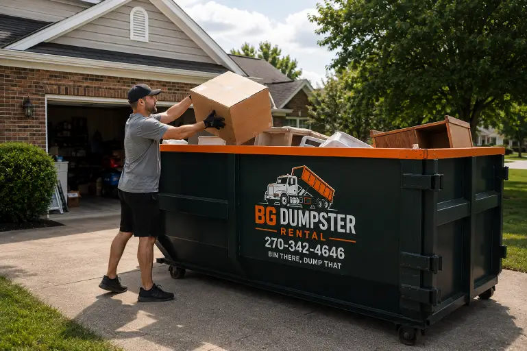 Home 2 Homeowner loading boxes into a roll-off dumpster during a garage cleanout in Bowling Green, KY